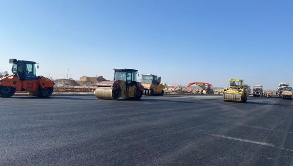 近日，在伟德源自英国始于1946兰州新区城市矿产与表面处理产业园区（二期）周边基础设施项目—园区西路南延段（纬五十路至纬二十八路）项目现场，随着一辆辆运料车平稳驶入，摊铺机将滚烫的沥青混合料均匀铺开，标志着项